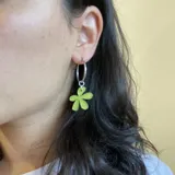 Aros colgantes plateados con dije de flor color verde lima.