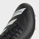 Championes de rugby Adidas modelo RS15 para terreno blando, con diseño en color negro y blanco. Presentan un exterior sintético suave, sistema de cordones asimétrico para mayor precisión al patear, cuello y talón acolchados para mayor confort, y suela con tapones metálicos diseñada para terrenos blandos.
