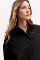 Camisa de algodón color blanco, de corte relajado y estilo western. Presenta detalle de tachas metálicas en la parte superior delantera y mangas largas con puños.
