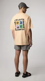 Camiseta color salmón de manga corta, confeccionada en algodón orgánico. Presenta un estampado gráfico en la espalda con diseño cuadrado y texto alrededor.