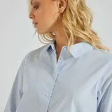 Camisa celeste a rayas verticales blancas, de corte recto, manga larga y cuello italiano.