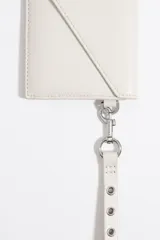 Billetera tipo sobre de Bimba y Lola, color blanco, con cierre de solapa y snap. Incluye un asa de mano extraíble con ojetes metálicos y logo estampado en el frente.