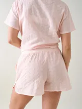 Short de broderie de algodón color blanco, con cintura elastizada, bolsillos laterales y botones decorativos frontales.