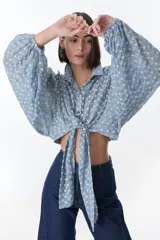 Blusa negra con escote en V, mangas largas abullonadas y lazo para atar en la parte delantera.