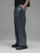 Pantalón cargo de corte oversize confeccionado en microfibra técnica. Presenta cintura elástica, bolsillos laterales y un bolsillo cargo con cierre de broche snap. Incluye un sistema de elásticos con tancas en los tobillos para regular la apertura y la silueta.
