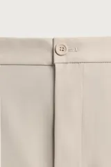 Pantalón regular fit color negro de corte recto, con cintura elástica en los laterales, trabillas, bolsillos frontales y cierre con botón y cremallera.