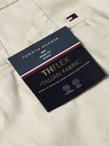 Pantalón de algodón elástico color crema con estampado integral de monogramas TH tonales en jacquard. Tiene dos bolsillos abiertos en la cadera y dos bolsillos traseros con botón.