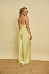 Musculosa de satén color amarillo suave, con tirantes finos, detalles de encaje en el escote y diseño asimétrico en el ruedo.