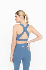 Top deportivo color celeste, con espalda cruzada y compresión alta.