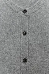 Chaqueta de tejido de punto color verde musgo, de corte cropped, con cuello redondo y cierre frontal de botones oscuros.