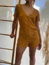 Mono corto color ocre con encaje floral, escote en V y mangas cortas.