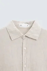 Camisa de corte regular fit confeccionada en tejido de lino, con cuello solapa, manga larga con puños abotonados y cierre frontal de botones.