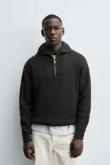 Jersey negro de punto perlado con cuello perkins y cierre frontal de cremallera.