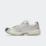 Championes Asics modelo Gel 1130, color blanco y plateado con detalles en negro, confeccionados con malla transpirable y revestimientos sintéticos, inspirados en el diseño de running de 2008 y equipados con tecnología GEL en el talón.