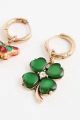 Aro tipo argolla dorada con dije colgante de trébol de cuatro hojas en color verde, con un pequeño cristal en el centro.