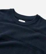 Buzo azul marino de algodón texturizado, con cuello redondo y mangas largas con puños ajustados.