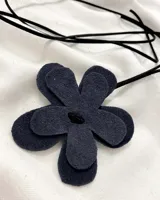 Gargantilla con dije de flor de cuero negro y cordón largo del mismo material.