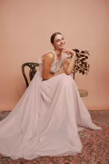 Vestido largo de tul plumetí en color rosa suave, con detalles de encaje bordado en el torso y volados en los hombros.