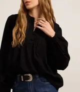 Blusa tipo bata confeccionada en voile color negro, con cuello padre con botones en la vista, recorte V en el busto y mangas largas.