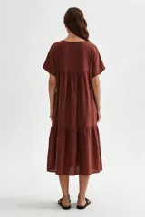 Vestido midi marrón de corte holgado, con escote en V, mangas cortas y detalle de volados fruncidos en el pecho y en el ruedo.