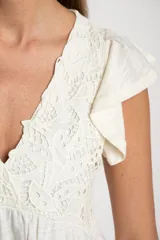 Remera color crudo de algodón con calados, corte al cuerpo y mangas cortas con volados.