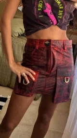 Falda corta de cuero en tono marrón con acabado desgastado, presenta bolsillos laterales grandes e irregulares y costuras decorativas visibles.