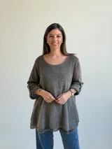 Sweater de punto color marrón chocolate, con escote redondo, mangas tres cuartos con trabilla y botón, y diseño holgado y acampanado.