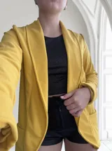 Blazer amarillo mostaza de crepe con solapas y bolsillos delanteros.