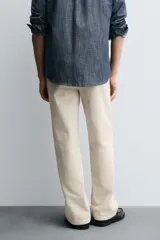 Pantalón chino de algodón color beige claro, corte recto, con cierre frontal de cremallera y botón, bolsillos delanteros y bolsillos traseros de doble vivo con botón.