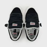 Zapatillas urbanas de corte bajo en color negro, fabricadas en gamuza con suela de goma blanca, cordones gruesos negros y etiqueta con logo en la lengüeta.