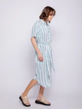 Vestido camisero midi azul con estampado floral blanco, corte recto, cuello camisero, mangas cortas, bolsillos laterales y lazo ajustable en la cintura.