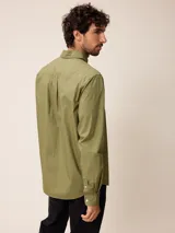 Camisa de manga larga en color blanco, confeccionada en algodón. Presenta cuello abotonado, cierre frontal con botones y un bolsillo en el pecho.