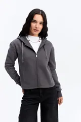 Campera tipo hoodie de algodón en color gris oscuro, con cierre frontal completo, capucha con cordones ajustables y bolsillos laterales. Presenta un diseño minimalista con logo bordado sutil en el pecho.