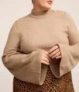 Sweater de punto color beige, con cuello alto y mangas largas acampanadas.
