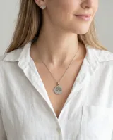Set de joyería compuesto por collar con dije circular y caravanas a juego, ambos con diseño grabado de árbol de la vida. Realizados en acero inoxidable.