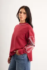 Buzo oversize de algodón con spandex, color verde menta, de manga larga con diseño de flores bordadas en rojo en las mangas y cuello redondo.