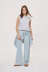 Pantalón wide leg de tiro medio con estampado de rayas verticales, diseño de cinco bolsillos, presillas para cinto y cierre frontal con botón y cremallera.
