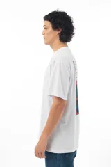 Remera blanca de algodón con estampa en la espalda de la Pantera Rosa cuidando bonsáis, con fondo de enrejado.