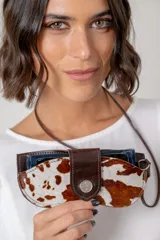 Cuelga lentes de cuero vacuno con diseño de pelo vacuno estampado tipo animal print. Cuenta con cierre de broche metálico y correa larga para colgar.