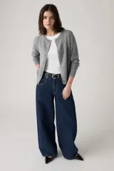 Jean de corte baggy y silueta barrel, confeccionado en denim rígido de color azul oscuro. Presenta costuras laterales curvadas que definen su forma característica, tiro alto y cierre frontal con botón y cremallera.
