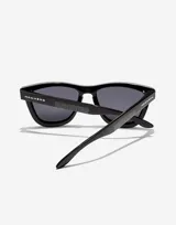 Lentes de sol Hawkers modelo ONE VENM RAW, de la colección Paula Echevarría. Montura cuadrada negra con lentes grises.