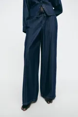 Pantalón de jean estilo wide leg en color azul oscuro, con cintura elástica y cordón ajustable. Presenta costuras verticales decorativas en el frente y bolsillos laterales.