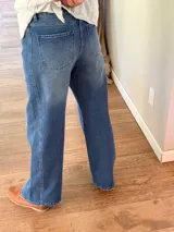 Pantalón de jean azul con corte holgado y detalle de tres cruces bordadas en el muslo derecho. Presenta costuras reforzadas y cierre frontal con botón metálico.