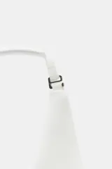 Top blanco de cuello halter y hombros descubiertos, con detalle de lazos en el delantero y cierre en la espalda con tira ajustable.