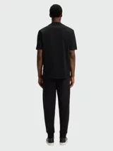 Remera de corte regular, color negro, con cuello redondo y detalle de monograma metálico en el pecho.