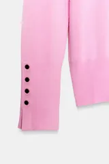 Jersey Zara de punto liso color negro, con cuello redondo, manga larga y detalle de botones dorados en los puños.