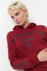 Canguro beige de algodón con capucha, manga larga y estampado frontal con la leyenda "Sport Club 23". También tiene estampado en las mangas.