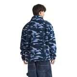 Campera de polar tipo sherpa con estampado camuflado en tonos azules y negros. Presenta cuello alto, cierre frontal completo y un bolsillo vertical con cierre en el pecho en contraste de color negro.