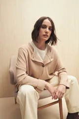 Sweater color beige de tejido de punto con cruce irregular y botones a contraste.