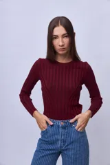 Top de punto ajustado al cuerpo, color bordó, con cuello redondo y mangas largas. Presenta un diseño acanalado vertical con costuras decorativas que forman una silueta en el frente.